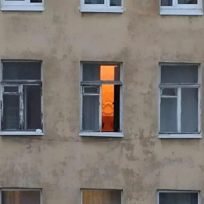 Building window shows a lit bathroom with toilet inside in cursed images