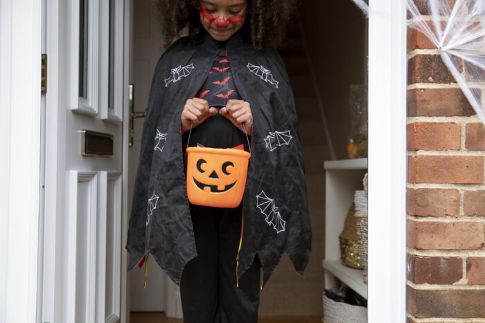 A young child in a Halloween cape holding a pumpkin basket after a husband decides it is grounds for divorce.
