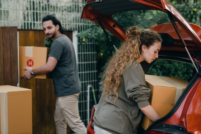 A couple loading cardboard boxes into the trunk of a car after grounds for divorce.
