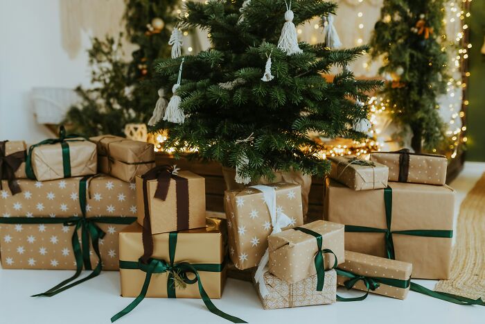 Christmas tree with gifts wrapped in brown paper and green ribbons under it
