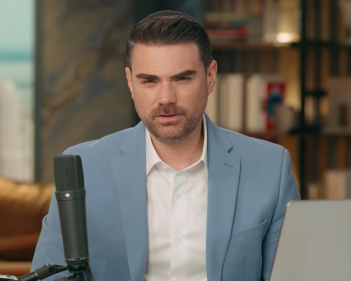 Man in blue blazer speaking into microphone indoors Man in blue blazer speaking into microphone indoors