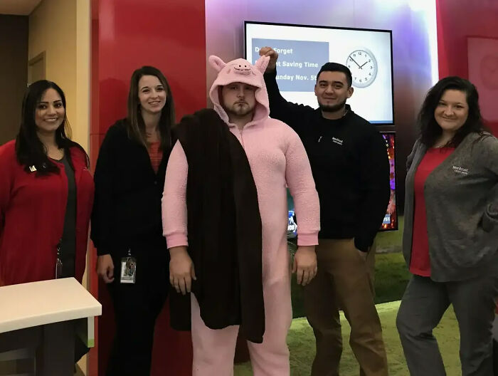 Funny Halloween photo of office workers standing together while one wears a pink pig Onesie