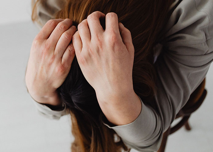 Overhead view of a person holding their head in frustration while solving strange online mysteries.