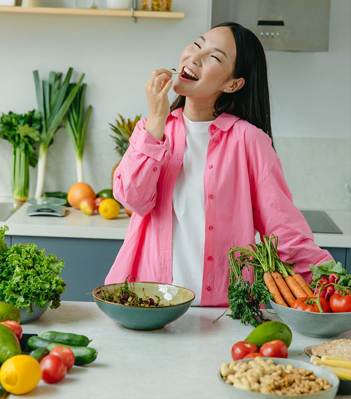 Happy woman enjoying fresh healthy vegetables in kitchen, discussing how often you should be going to the toilet. Happy woman enjoying fresh healthy vegetables in kitchen, discussing how often you should be going to the toilet.