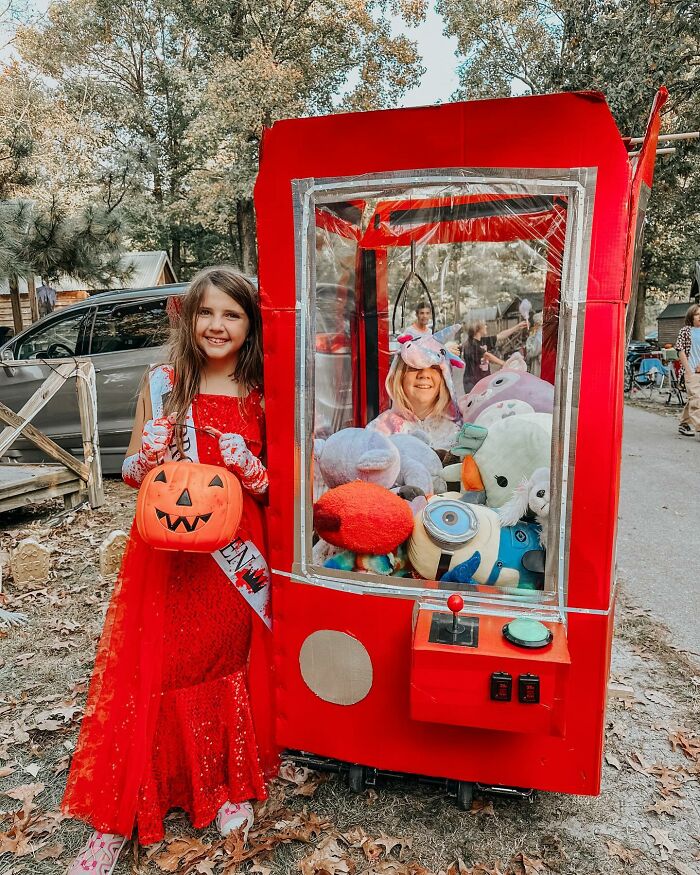 A girl in a claw machine wheelchair costume next to a friend trick-or-treating