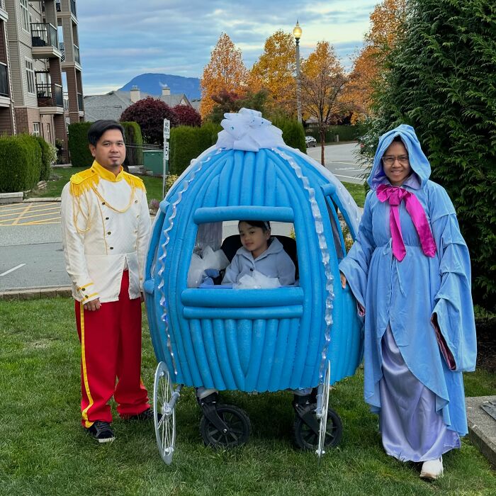 A family dressed in Cinderella-themed Halloween costumes featuring a wheelchair carriage