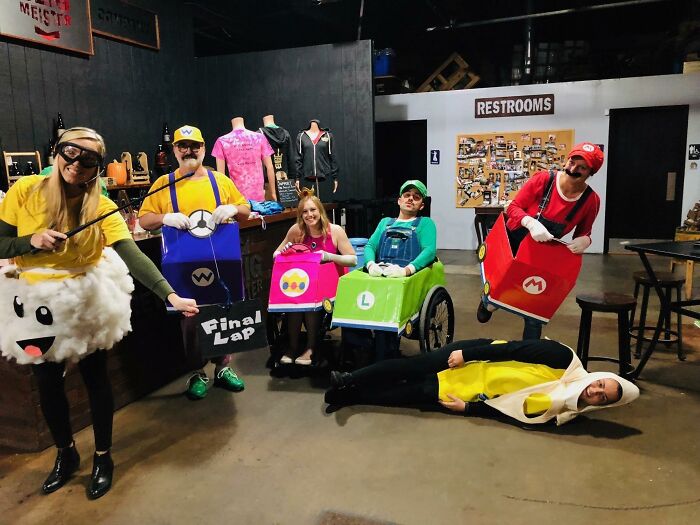 Group of creative people with disabilities in Mario Kart wheelchair costumes celebrating Halloween.