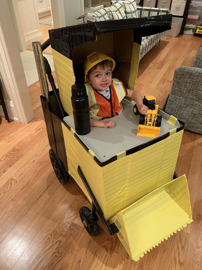 Young boy in a wheelchair disguised as a yellow bulldozer for creative Halloween fun.
