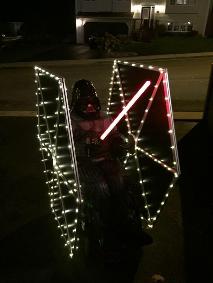 Child in Darth Vader suit seated in a wheelchair illuminated like a TIE fighter for people with disabilities Halloween