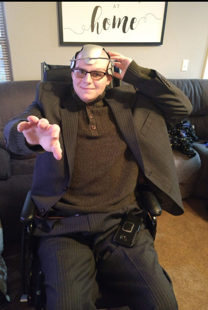 Man in suit and Cerebro helmet in wheelchair posing as Professor X, showing creative people with disabilities