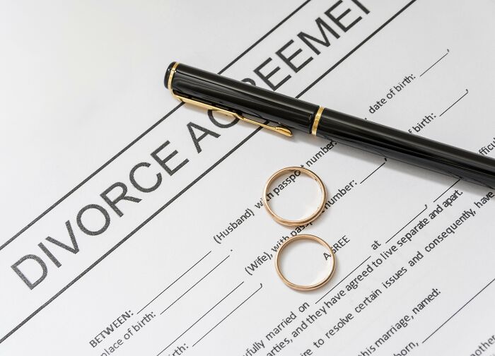 A divorce agreement document with two wedding rings and a black pen