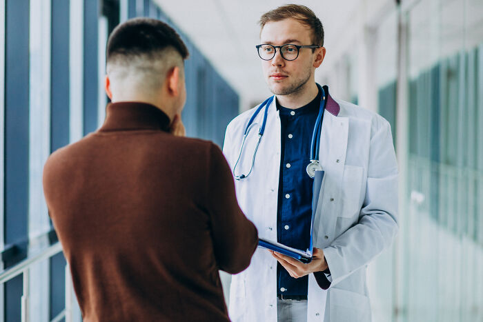 Doctor in white coat speaking with a patient, reflecting industry insiders in medical companies.