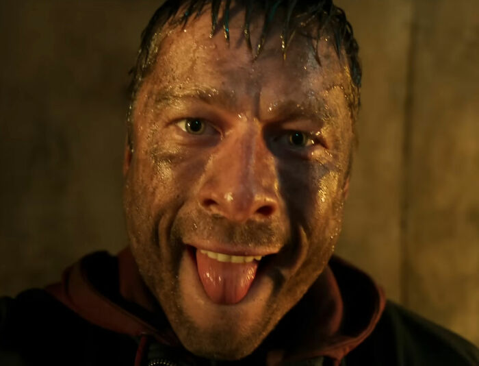 Close-up of a dirty, smiling character in a Stephen King Remake scene