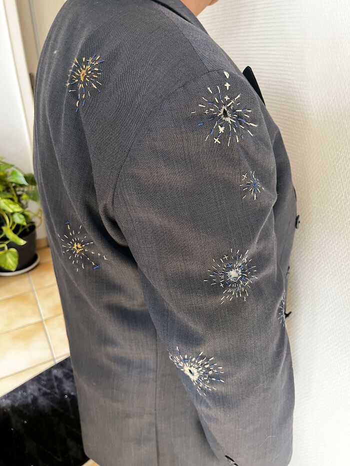 A gray jacket sleeve decorated with starburst embroidery patches, showing how creativity can save money on fashion