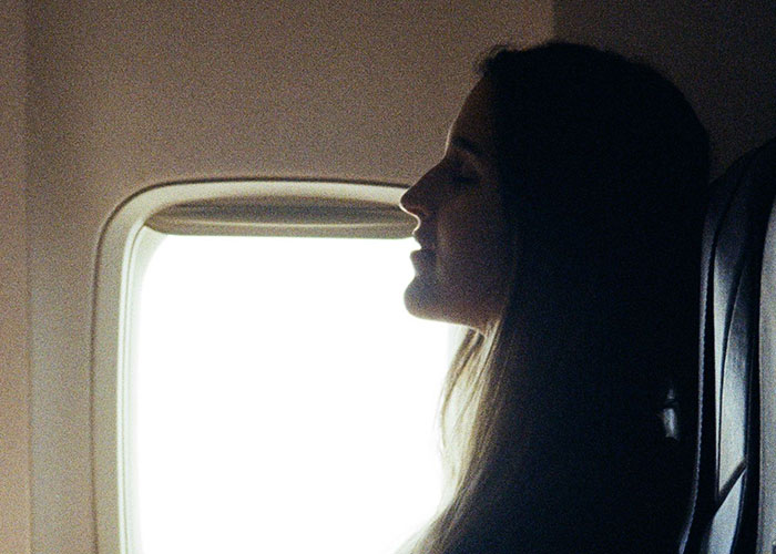 Passenger looking out airplane window on flight amid entitled passenger