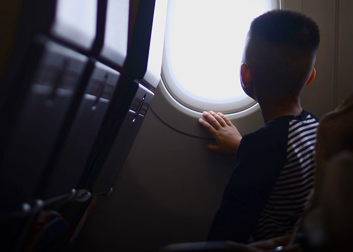 Child looking out airplane window at 30000 feet flight view