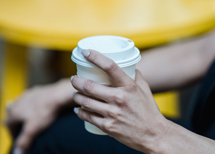 Close-up of hand holding coffee cup during flight