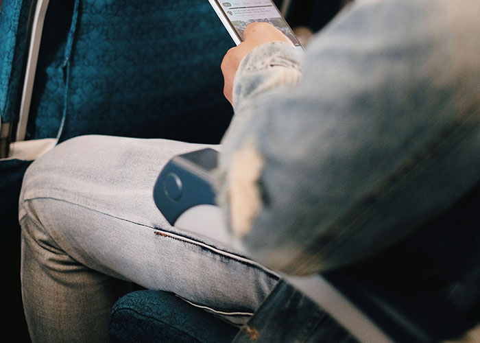 Person using phone in airplane seat with limited space