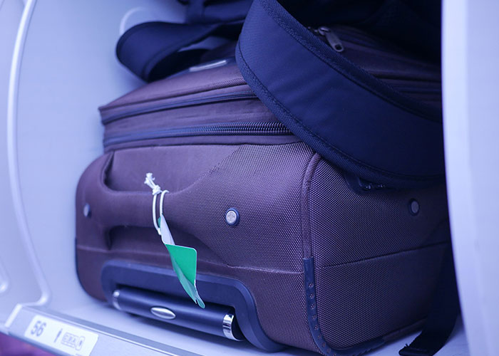 Suitcase in airplane overhead compartment during flight