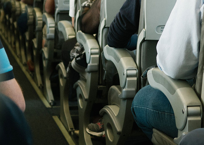 View of airplane seats with passengers seated closely together