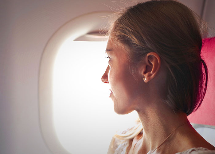 Woman passenger looking out airplane window thoughtfully