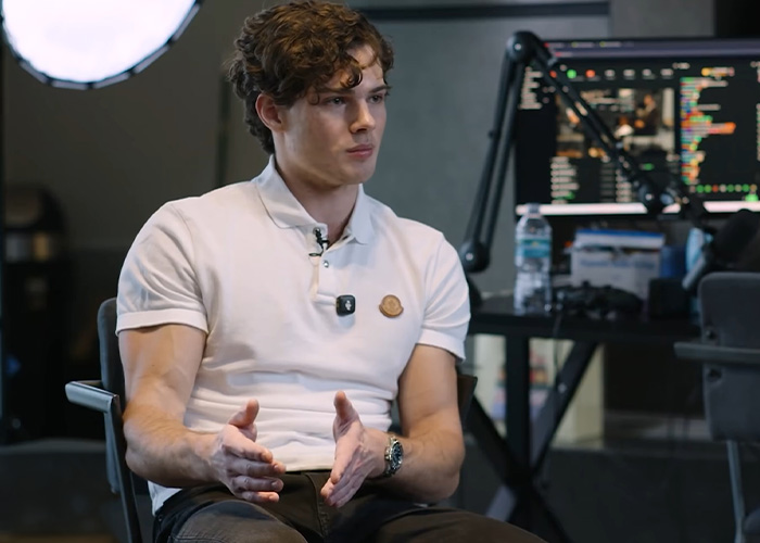 A young man gesturing during an interview discussing looksmaxxing camp procedures. A young man gesturing during an interview discussing looksmaxxing camp procedures.