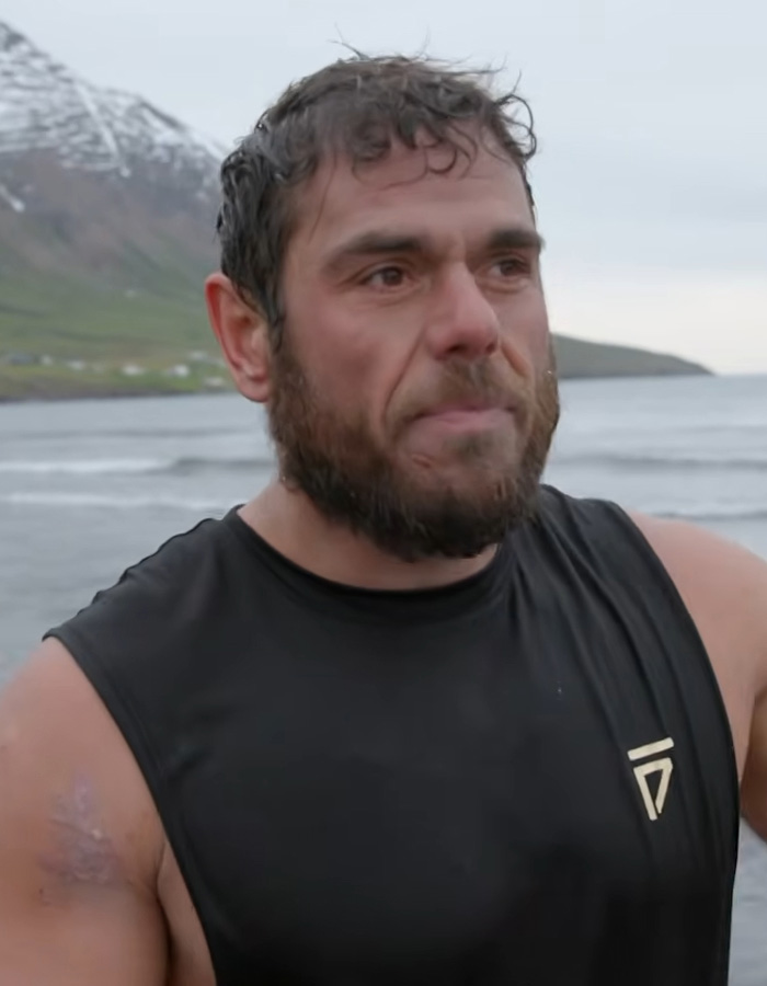 Extreme swimmer standing on a coastal shore near cold ocean waters looking tired after completing a swim challenge Extreme swimmer standing on a coastal shore near cold ocean waters looking tired after completing a swim challenge