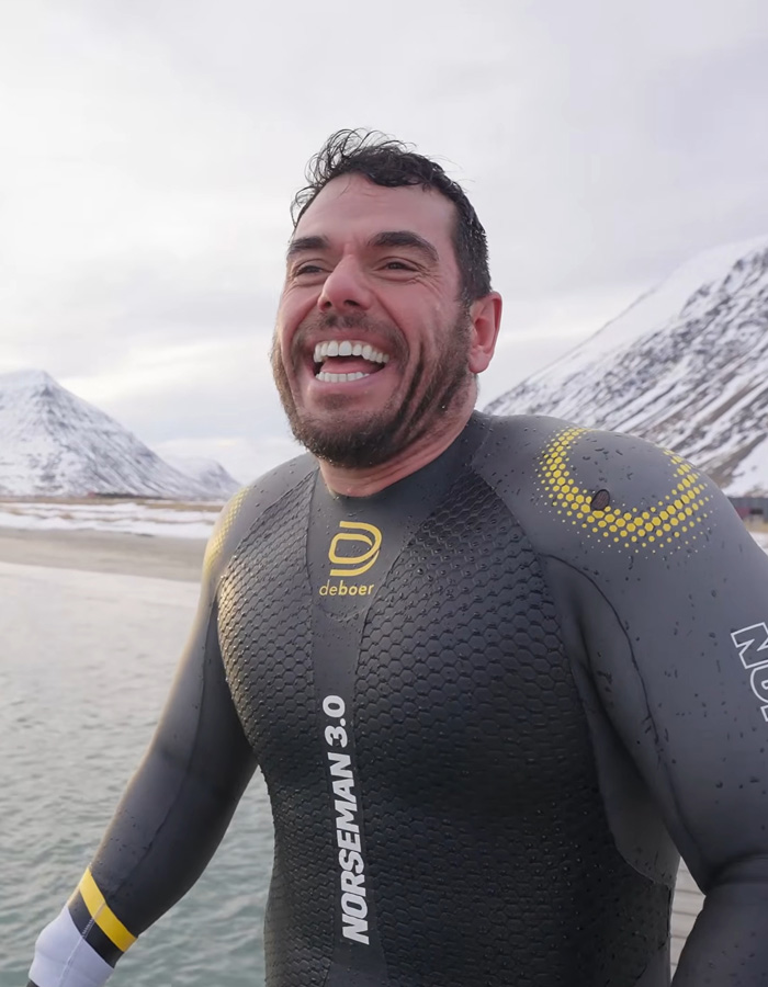 Extreme swimmer smiling in a wetsuit in front of snowy mountains. Extreme swimmer smiling in a wetsuit in front of snowy mountains.