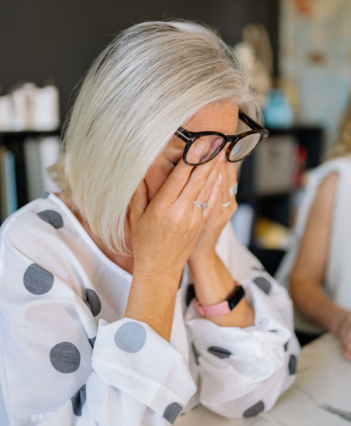 A worried mom covering her face with her hands after finding out who her son’s GF is. A worried mom covering her face with her hands after finding out who her son’s GF is.