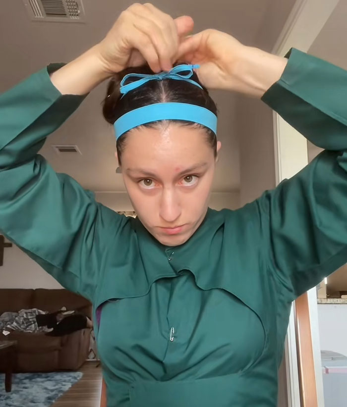 Lovina Zook tying a blue ribbon hairband, sharing her Amish background Lovina Zook tying a blue ribbon hairband, sharing her Amish background