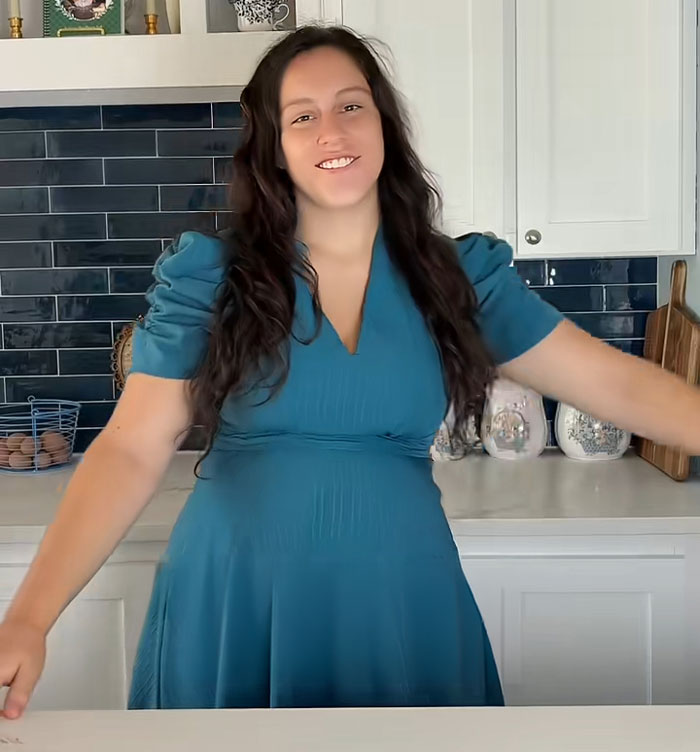 Lovina Zook smiling in a stylish blue dress in her kitchen after growing up Amish. Lovina Zook smiling in a stylish blue dress in her kitchen after growing up Amish.