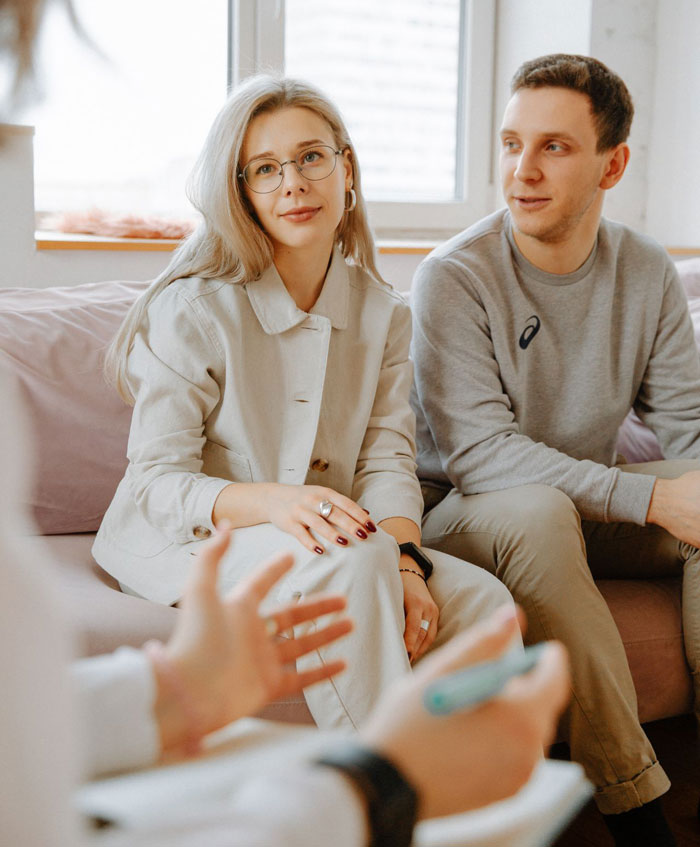 Young man and older woman sitting together on a couch speaking with someone out of frame. Young man and older woman sitting together on a couch speaking with someone out of frame.