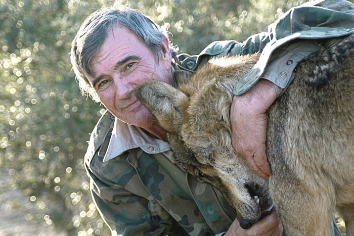 Marcos Rodríguez Pantoja smiling and embracing a wolf in a forest setting Marcos Rodríguez Pantoja smiling and embracing a wolf in a forest setting