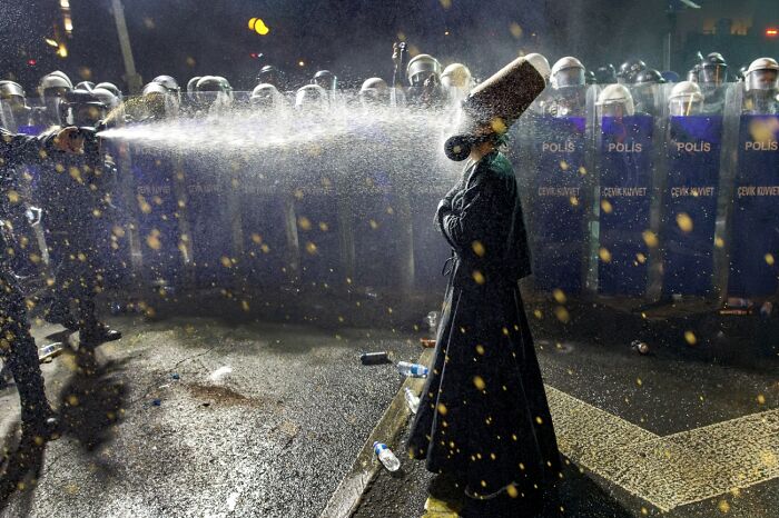 Protester sprayed with water by police during night protest with riot shields
