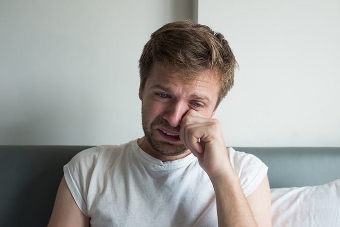 Distressed man wiping away tears, showing heartbreak after a dream proposal turned into a total nightmare.
