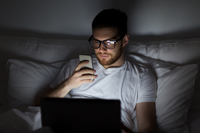 A guy lying in bed at night looking at his phone after a dream proposal turned into a nightmare.