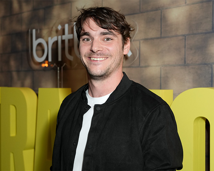 RJ Mitte smiling in a black jacket and white shirt at an event. RJ Mitte smiling in a black jacket and white shirt at an event.