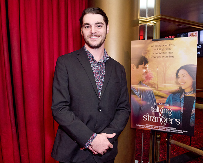 RJ Mitte posing near a movie poster before his tragic passing at 34. RJ Mitte posing near a movie poster before his tragic passing at 34.