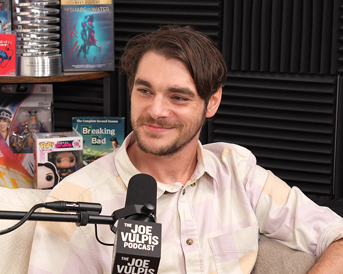 Actor RJ Mitte smiling during a podcast recording at a microphone. Actor RJ Mitte smiling during a podcast recording at a microphone.