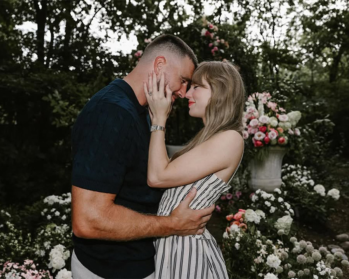 Taylor Swift holding Travis Kelce outdoors surrounded by floral wedding decor Taylor Swift holding Travis Kelce outdoors surrounded by floral wedding decor
