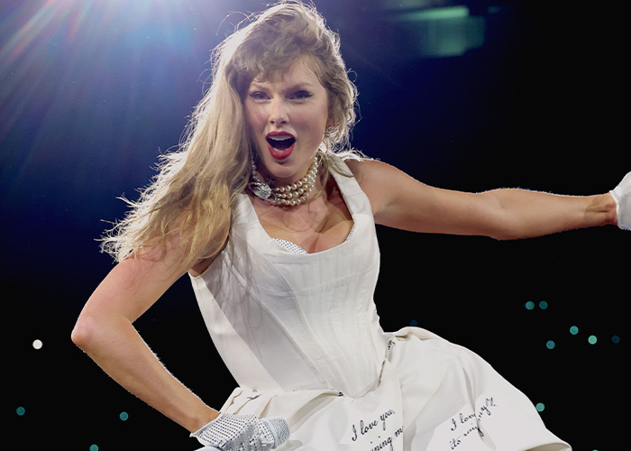 Singer Taylor Swift performing on stage wearing a white dress reminiscent of wedding decor aesthetics Singer Taylor Swift performing on stage wearing a white dress reminiscent of wedding decor aesthetics