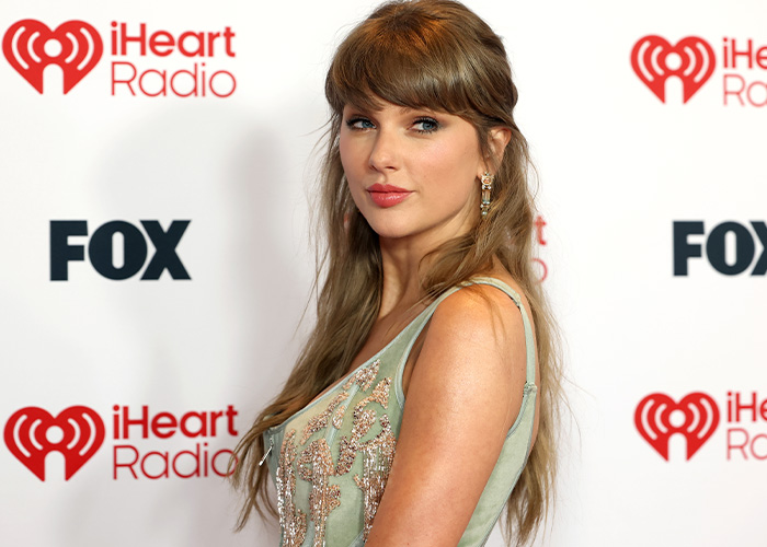 Singer Taylor Swift posing on a red carpet with iHeartRadio logo background Singer Taylor Swift posing on a red carpet with iHeartRadio logo background