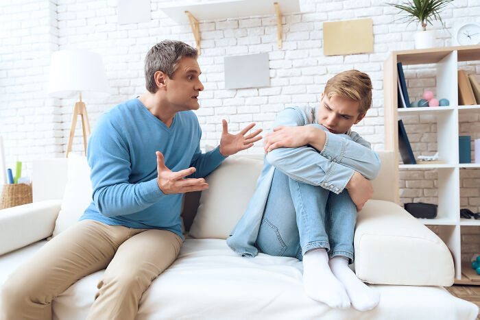 Anxious young boy on sofa being yelled at by father representing being disowned by their families