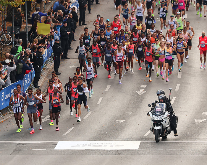 A crowd of runners competing in a marathon with a police motorcycle lead A crowd of runners competing in a marathon with a police motorcycle lead