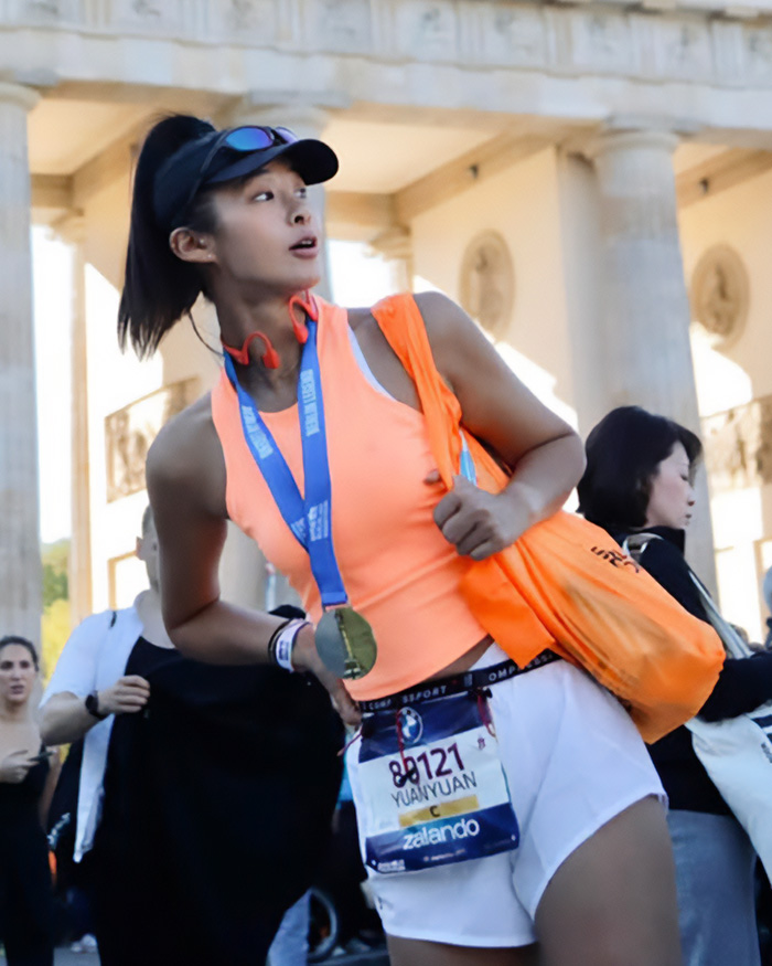 A fitness influencer wearing marathon bib number 80121 in front of a landmark A fitness influencer wearing marathon bib number 80121 in front of a landmark