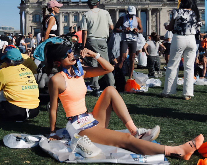 A fitness influencer sitting down on the grass posing after a marathon A fitness influencer sitting down on the grass posing after a marathon