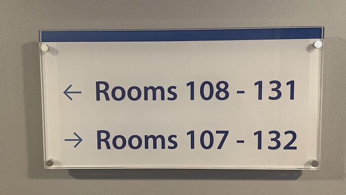 A directional wall sign pointing to overlapping room numbers, one of many absurd signs and moments.