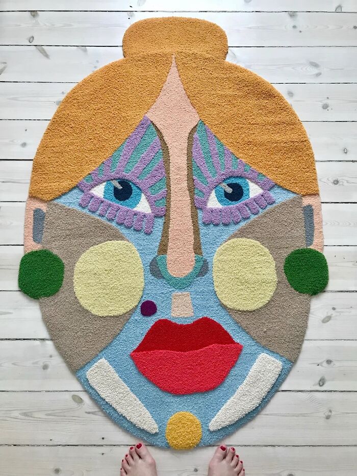Large colorful tufted face rug displayed on a wooden floor by Ina Dyreborg