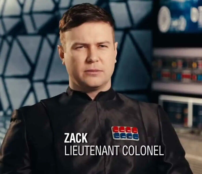 An actor in a futuristic military uniform with badge details, representing creative movie props.