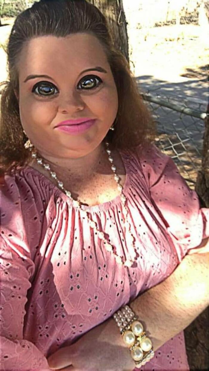 Woman with exaggerated large eyes in pink dress and pearl jewelry